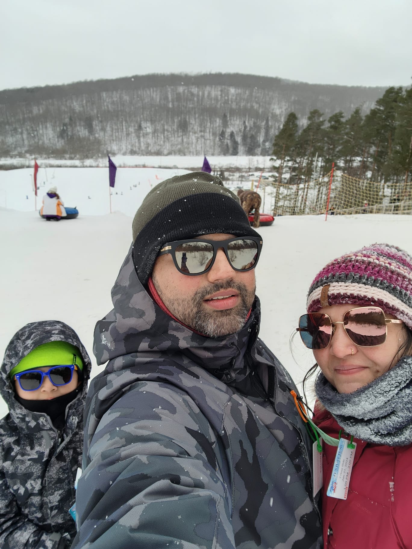 Pooja with her husband and son on a snowy tubing day