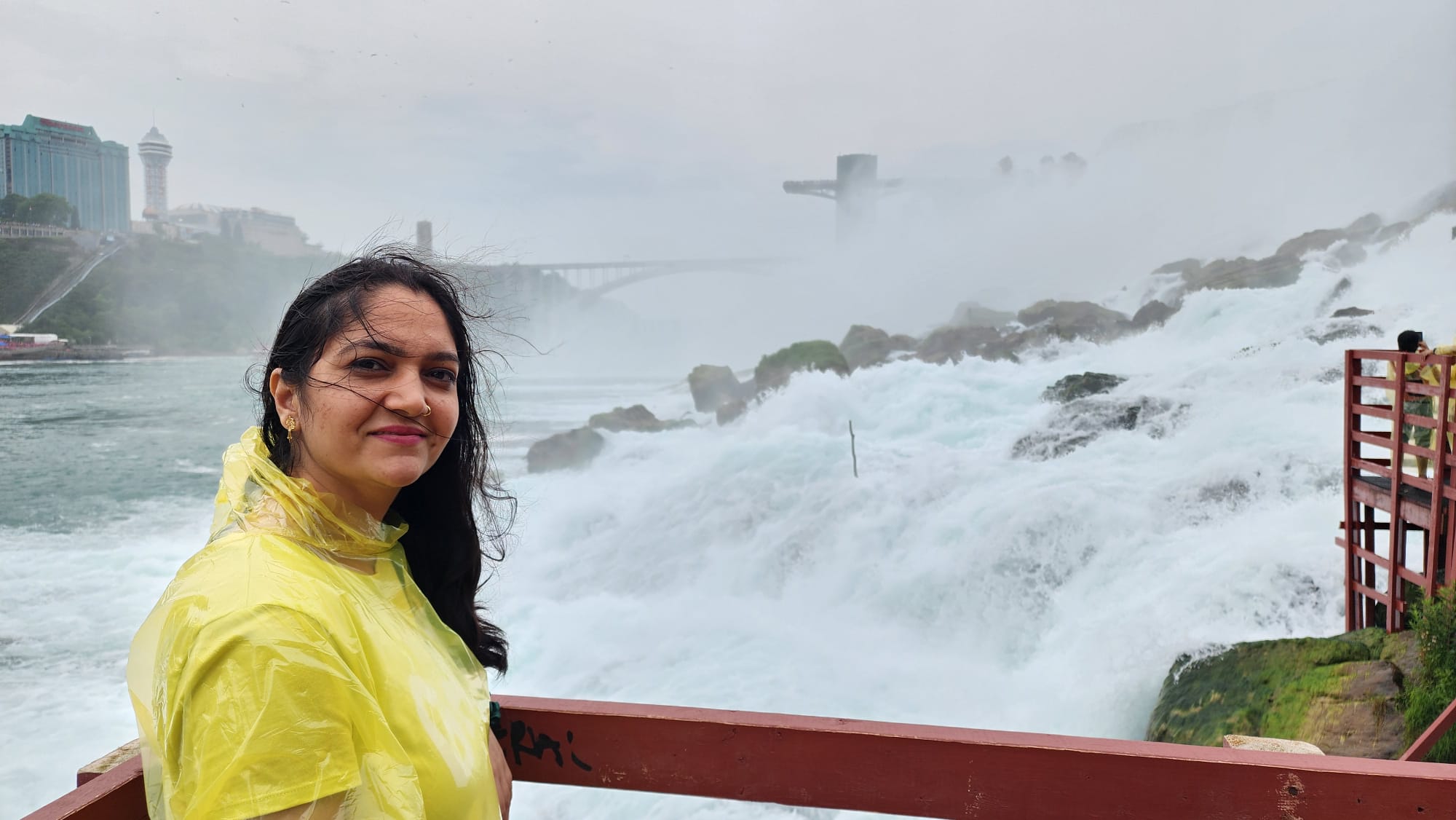 Pooja at Niagara Falls, mist rising behind her